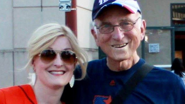 Rebecca Howell, Ph.D., stands beside her father, Robert Hall. He has his arm around her, and they're both smiling as they look at the camera.
