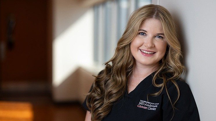 Smiling blonde woman with curled hair and a black MD Anderson polo shirt.
