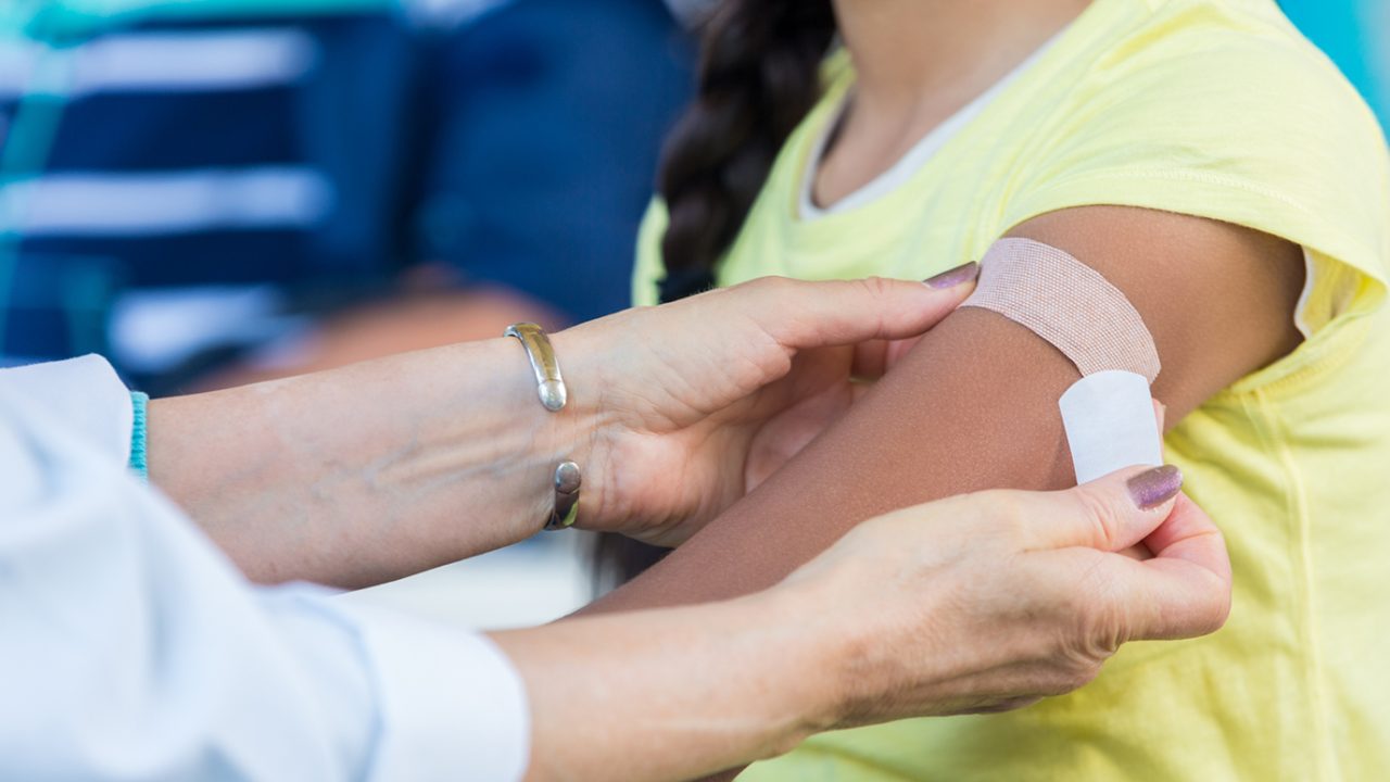 Physician applies band-aid after giving HPV vaccine