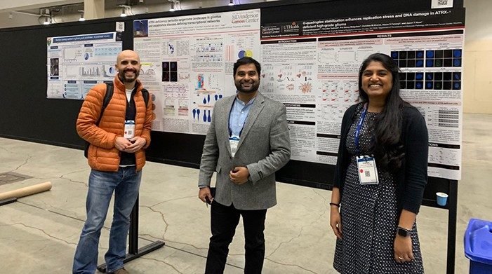 Three lab members stand in front of their posters