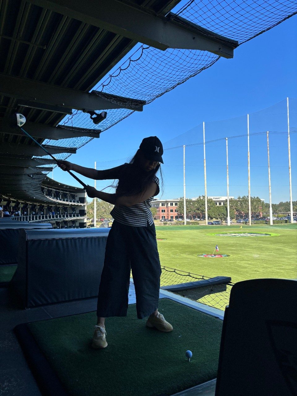 Person standing in the shade post-swing at TopGolf